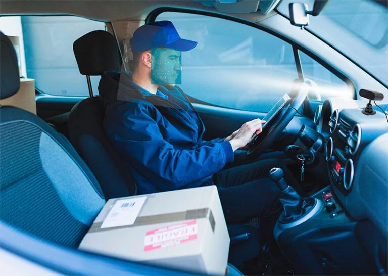 Visão interna de motorista sendo monitorado por câmera de fadiga no painel, detectando distrações e sonolência via inteligência artificial da Cellblock.